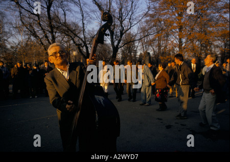 Belgrado sotto sanzioni : un uomo vecchio gioca double bass come la gente ballare, tenendo le mani in Veliki Kalemedan park, Dec 1993 Foto Stock