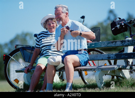 Per gli anziani. Coppia di anziani ciclisti in appoggio su una panchina nel parco. Foto Stock