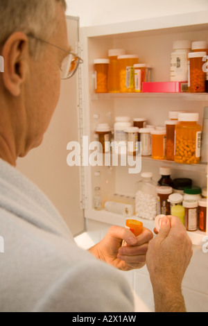 Guarda Senior per farmaci in medicina cabinet. Foto Stock