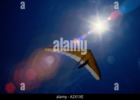 Skyward vista di deltaplano in volo contro il sole con lens flare. Foto Stock