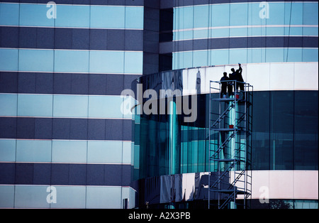Due uomini su impalcature esterne moderno edificio commerciale. Foto Stock
