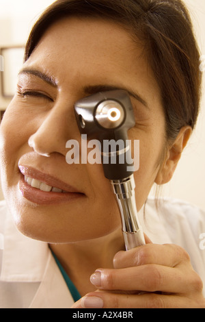 Medico femmina trattiene un otoscopio per il suo occhio durante un esame di pazienti un orecchio. Foto Stock