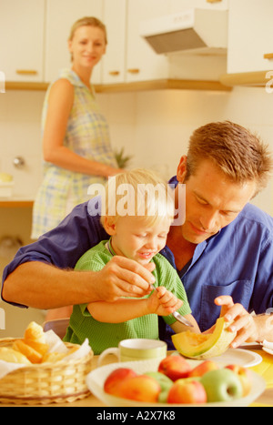 Famiglia all'interno. Padre con little boy mangiare e madre in background. Foto Stock