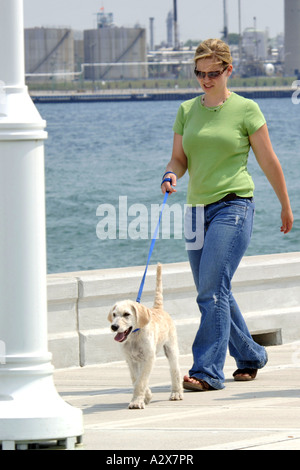 Giovane femmina adulta prendendo il suo cane per una passeggiata Foto Stock