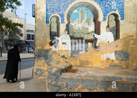 Fes el Bali Marocco Nord Africa Un vecchio uomo cammina oltre una parete murale dipinto di blu e di gate o il Bab Boujeloud Foto Stock