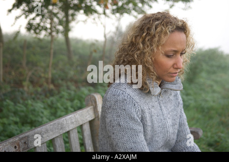 La donna da sola su una panchina nel parco Foto Stock