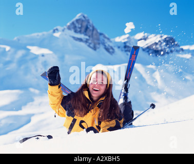 Stile di vita. La Svizzera. Donna sciatore giacente nella neve e agitando. Foto Stock