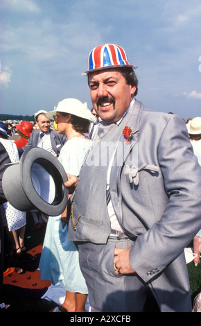 Giocando ad avere uno scherzo, uomo che indossa un cappello di plastica con bandiera Union Jack sotto il tradizionale cappello Epsom Downs Surrey Inghilterra giugno 1985 1980 UK HOMER SYKES Foto Stock