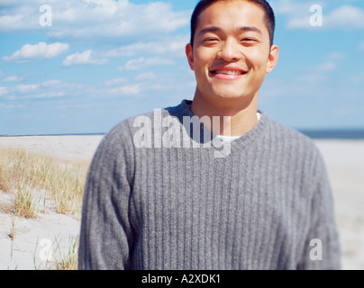 All'aperto in spiaggia Ritratto di giovane uomo che indossa un maglione grigio. Foto Stock