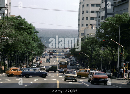 Scena di strada a l'Avana, Cuba, con il traffico su una strada che conduce al mare Foto Stock