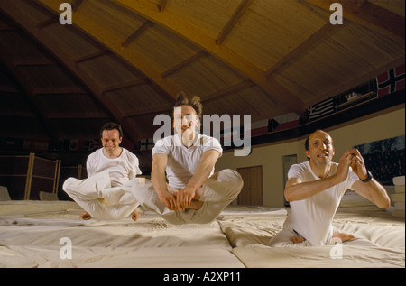YOGIC FLYING IMPLICA LA SEDUTA IN UNA PIENA posizione del loto e salto in avanti BOUNCY IMATERASSI. Foto Stock