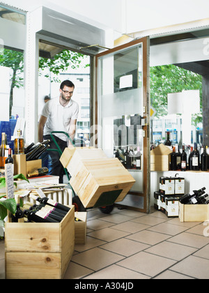 Uomo carrello di spinta delle scatole di vino in negozio Foto Stock