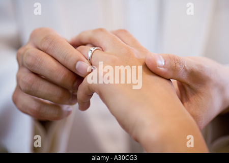 Lo sposo posizionando l'anello nuziale sul dito spose Foto Stock