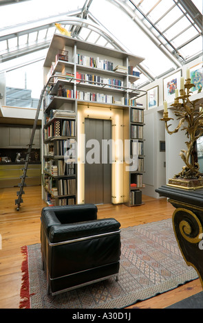 Soggiorno con nero sedia in pelle, libreria e ascensore ingresso in moderno appartamento attico Foto Stock