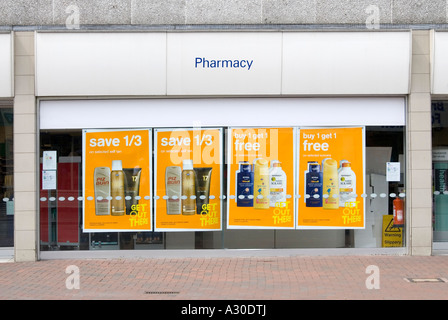 La finestra di visualizzazione di una tipica strada alta stivali farmacia succursale con poster promuovere offerte speciali sui prodotti abbronzanti Foto Stock