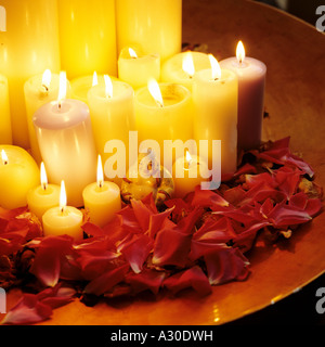 Candele accese in una coppa con petali di rosa e una statua di Buddha Foto Stock