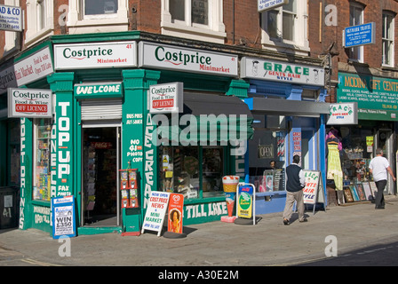 Costprice minimarket off angolo licenza shop e signori capelli stile barbieri shop sunny street scene in Brick Lane Shoreditch East London E1 England Regno Unito Foto Stock