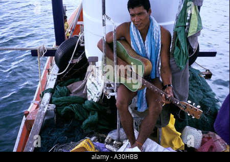 Un pescatore di suona la chitarra sulla sua barca in un porto su Koh Pha Ngan Isola, Thailandia Foto Stock