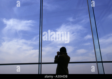 Una donna fotografa la vista su Kyoto dalla parte superiore della stazione di Kyoto in piedi di fronte ad una grande finestra in vetro. Kyoto, Giappone Foto Stock