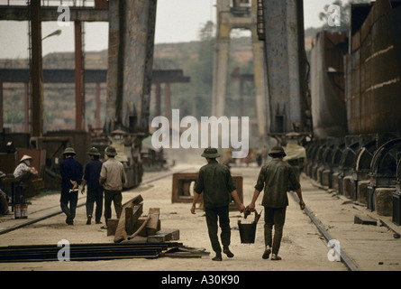 Il Vietnam 1994 due lavoratori portante una benna tra di loro nella baia di Ha Long shipyard il cantiere è disperata per più ordini di lavoro è la riparazione di navi vecchie 1994 Foto Stock