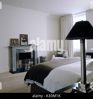 Camera da letto con mantelpiece e moderna paralume al posto letto Foto Stock