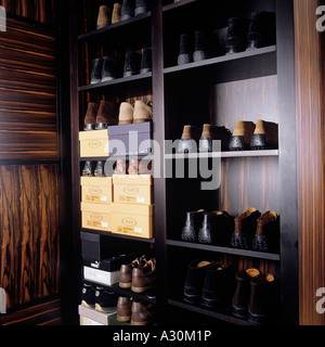 Paia di scarpe impilate ordinatamente su scaffali in un armadio in legno di noce Foto Stock