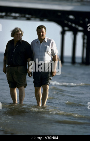 Grasso di due uomini stavano in piedi presso Shore di Blackpool Beach Foto Stock