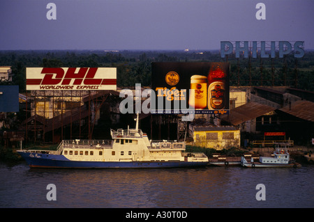 Dhl world wide express birra tiger GOOD AS GOLD in tutto il mondo e philips cartelloni su acqua in Ho chi minh city una piccola barca la signora rua passa davanti 1994 Foto Stock