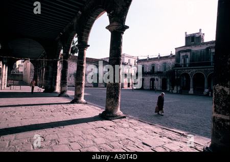 La gente a piedi attraverso un altrimenti vuota piazza del Duomo nelle prime ore del mattino, Havana, Cuba Foto Stock