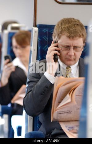 Royalty free fotografia di British business man con FT e telefono cellulare il pendolarismo su treni London REGNO UNITO Foto Stock