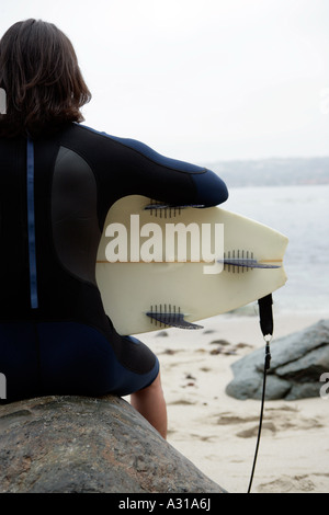 Vista di un uomo in possesso di una tavola da surf in attesa per l'onda perfetta. Foto Stock