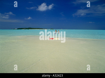 Asciugamani da spiaggia su sandbar con coppia camminando in surf alle Maldive Foto Stock