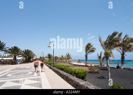 Giovane a piedi lungo la passeggiata dalla spiaggia di Playa de Las Cucharas, Costa Teguise, Lanzarote, Isole Canarie, Spagna Foto Stock