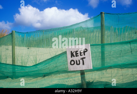 Dipinte a mano ruvida segno indicante Tenere fuori nella parte anteriore del nylon verde netting e filo e PECORA Recingendo sulle dune di sabbia Foto Stock