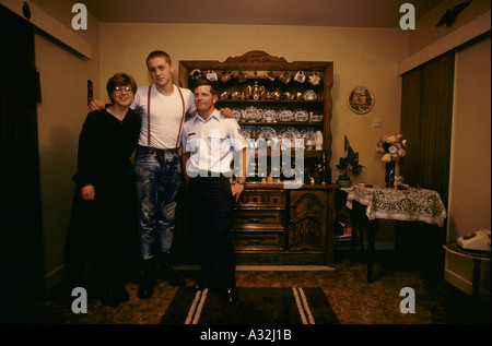 Raf lakenheath usaf base marito veteran con sua moglie skinhead figliastro in piedi nella parte anteriore del mobiletto in legno con varie piastre di teiere tazze piattini sul display interno la loro casa al di fuori della base Foto Stock