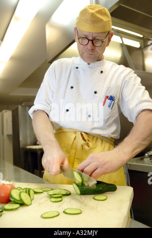 Il cuoco e lo chef de cuisine Stefan Voege in mensa cucina durante il taglio di vegetali Foto Stock