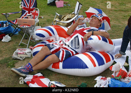 Uomo che indossa la piena unione jack outfit reclinata su un Blow up cuscino in parco, Inghilterra Foto Stock