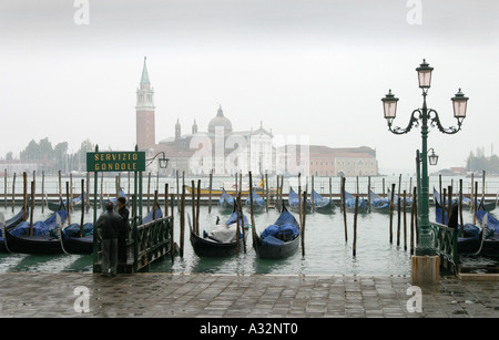 Gondole ormeggiate sul molo del canale con la Basilica di San Giorgio maggiore attraverso il Lido di Venetzia sullo sfondo, Venezia, Italia Europa Foto Stock