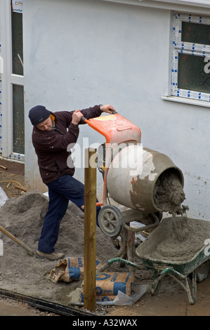 Un costruttore utilizzando un mescolatore di cemento sullo sviluppo di nuove case in Cornovaglia,Inghilterra Foto Stock