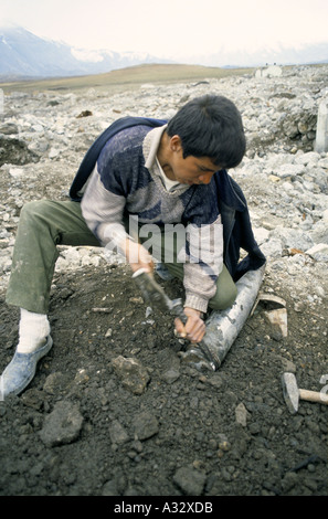 Rischio di morte: un ragazzo cerca di rimuovere la banda di ottoni da una bomba live in, Diyana Molla, Kurdistan iracheno. Foto Stock