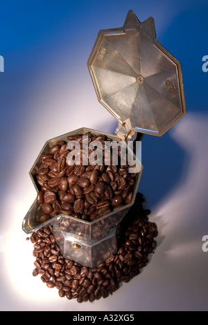 Stufa italiana top caffettiera circondato e piena di chicchi di caffè Foto Stock