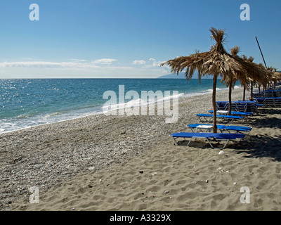 Vuoto spiaggia vicino da Kokkino Nero con sund lettini sdraio e ombrelloni coperto con foglie di palme Tessaglia Grecia Foto Stock