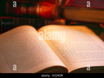 Vecchio libro giacente aperta sulla tabella delle pile di libri vecchi in background Foto Stock