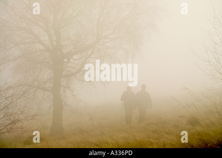 Walkers sul Cotswold modo in primavera la nebbia sul bordo comune, Gloucestershire Foto Stock