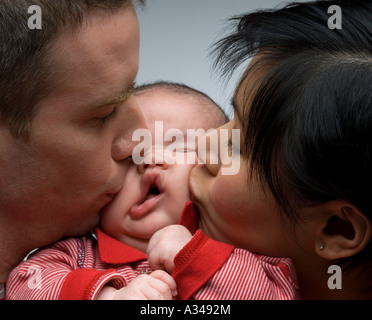 Caucasian padre e madre cinese kissing baby Foto Stock