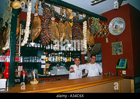 Essiccato con prosciutti e baristi in un tipico bar e ristorante, Siviglia, Spagna Foto Stock