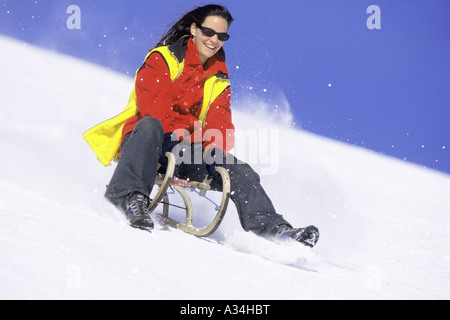 Donna taboggoning, Austria, Alpi Foto Stock