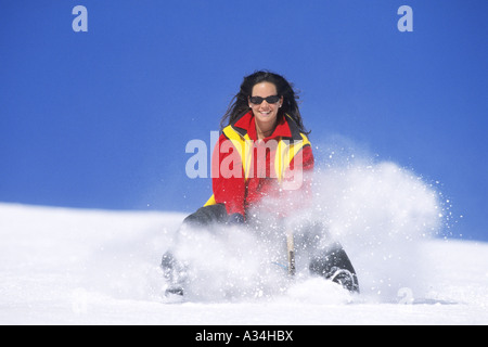 Donna taboggoning, Austria, Alpi Foto Stock