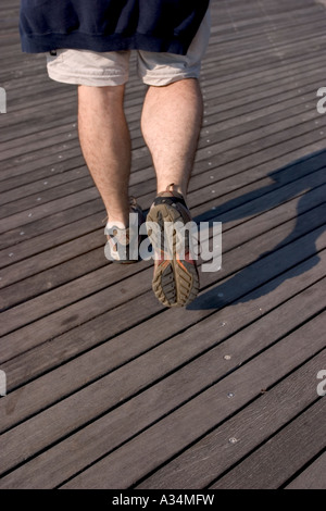 Gambe di uomo adulto camminando sulla terrazza in legno Foto Stock