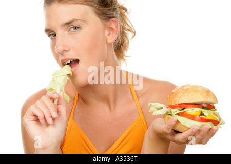 Giovane donna mangiare foglia di lattuga e burger Foto Stock